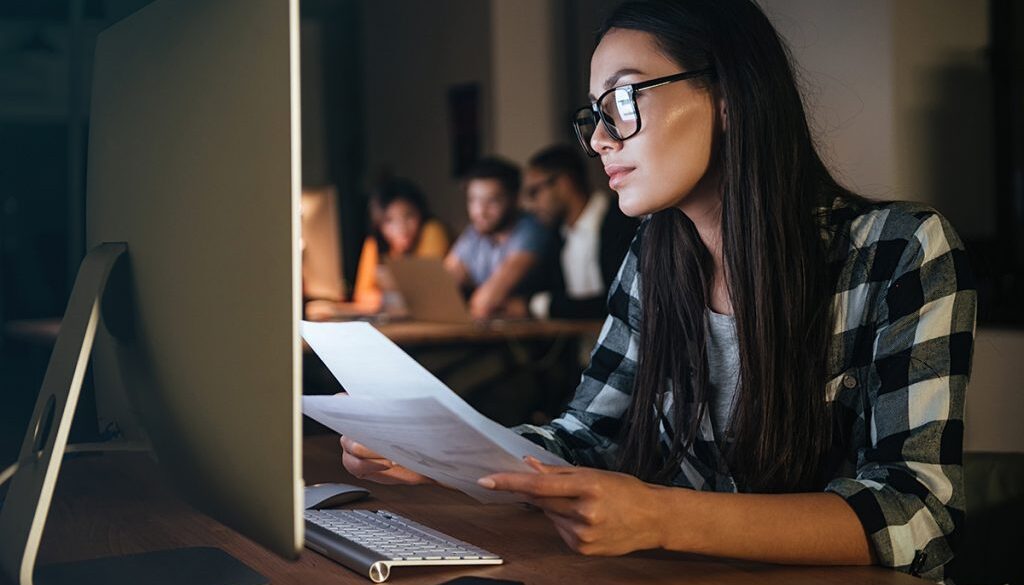 Concentrated businesswoman holding documents working late at night in office